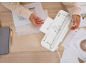 Une personne utilisant une plastifieuse blanche sur un bureau en bois avec des documents.