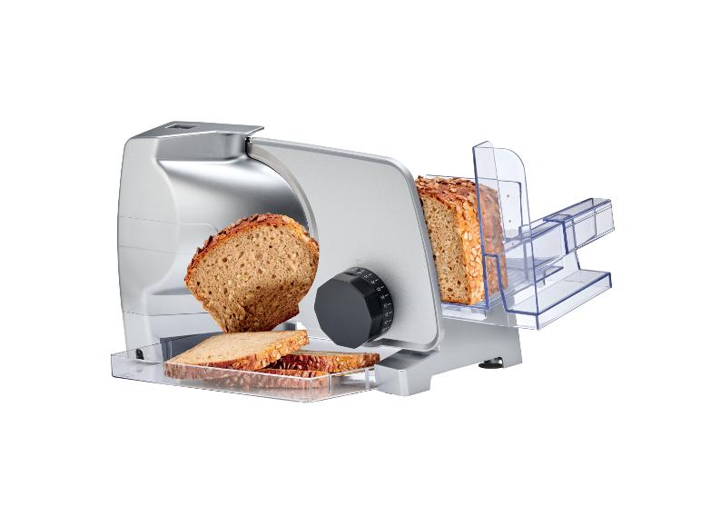 Trancheuse à pain électrique argentée avec du pain complet tranché.