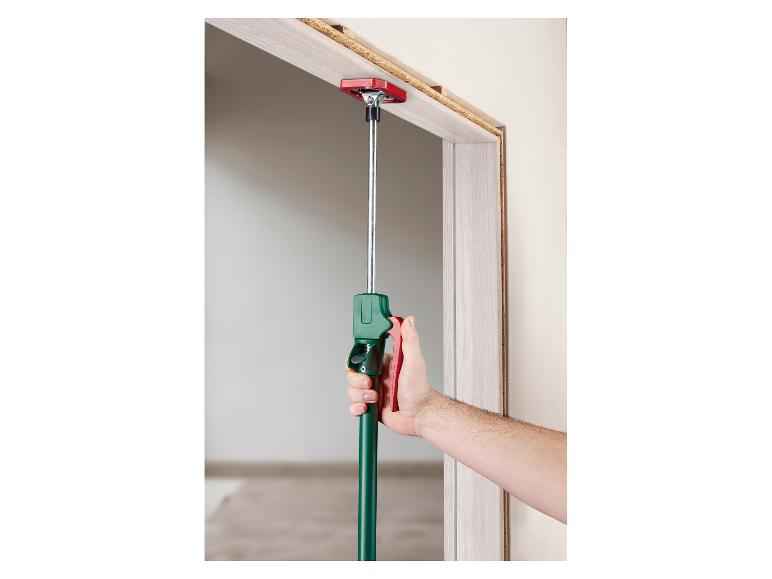 Un homme utilise un support de montage télescopique pour installer un cadre de porte.