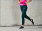 Une femme portant un legging vert foncé et des baskets noires.