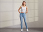 Une femme porte un débardeur blanc et un jean skinny bleu.