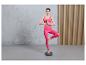 Une femme en leggings roses et un soutien-gorge de sport s'entraîne à l'équilibre sur un disque vert.