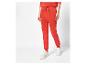 Une femme porte un pantalon de survêtement rouge et des baskets blanches