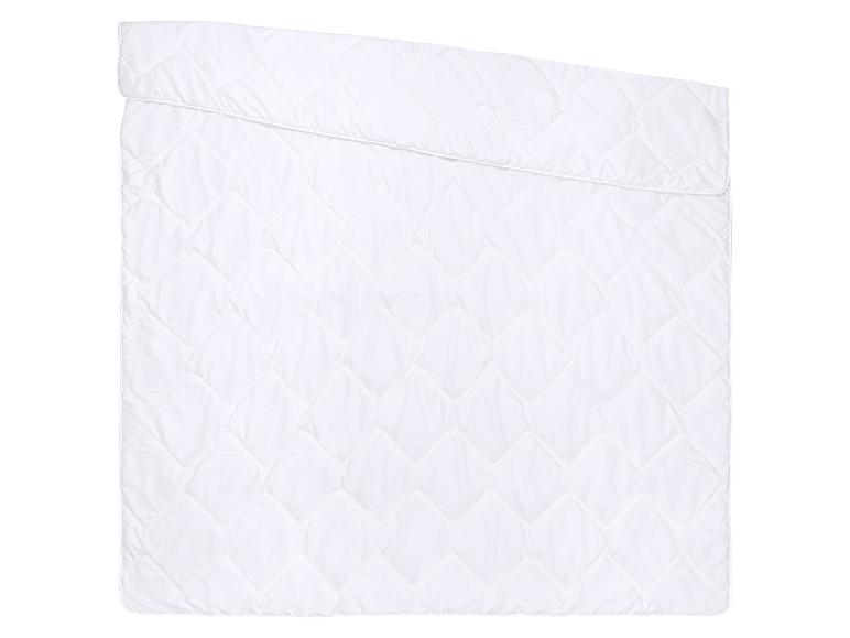 Couette blanche matelassée avec un motif de losanges, pliée sur le dessus.