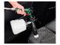 Un pistolet pulvérisateur vert avec une brosse pour nettoyer les sièges de voiture.