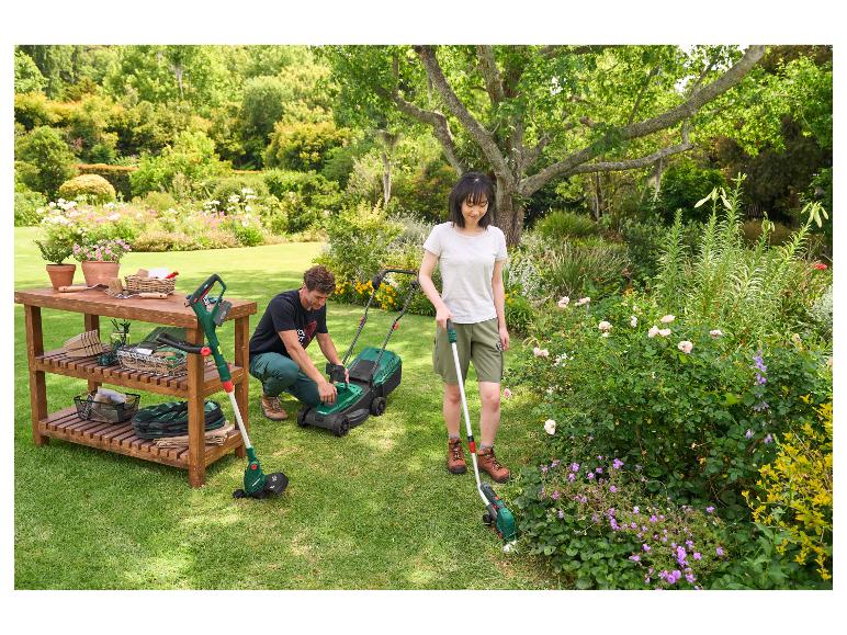 Homme et femme jardinant avec une tondeuse, un coupe-bordure et des outils de jardin sur un banc en bois.