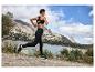 Femme courant en vêtements de sport Hoka One One dans un paysage montagneux.