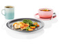 Une assiette grise avec du poulet rôti, des épinards et des tomates cerises, un bol rose avec de la soupe et une tasse bleue avec du café.