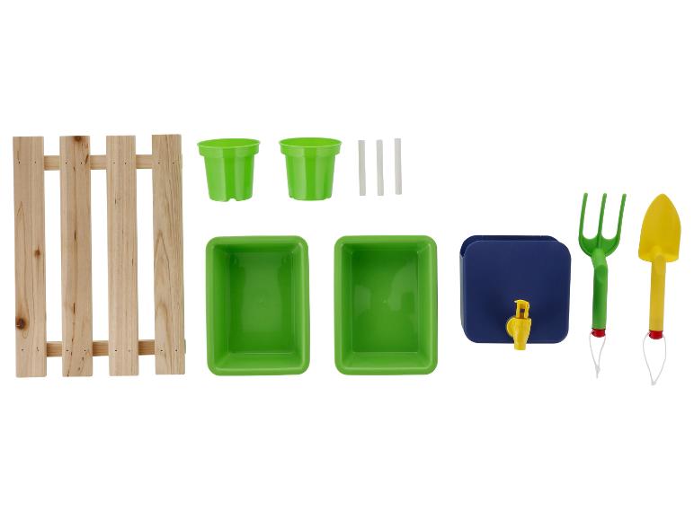 Ensemble de jardinage avec clôture en bois, pots verts, plateaux, distributeur d'eau bleu et outils.