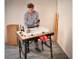Homme assemblant des meubles avec une perceuse sur un établi.