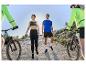 Trois athlètes en vêtements de sport Karrimor marchent sur un sentier de montagne à vélo.