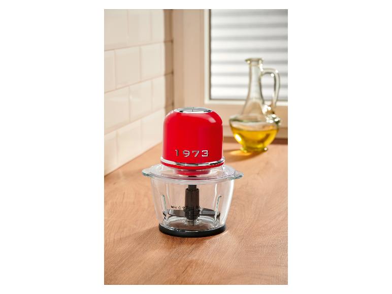 Hachoir rouge sur un comptoir en bois avec une bouteille d'huile en arrière-plan.