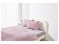 Un lit avec de la literie rose clair.