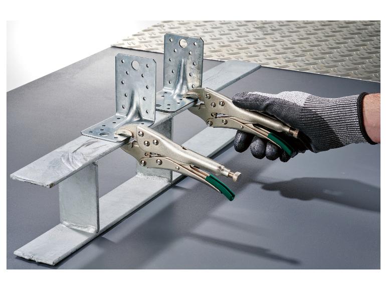 Main tenant un support métallique avec une pince, fixé à un profil métallique.