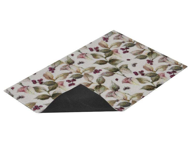 Tapis à motifs de feuilles et baies, avec envers antidérapant noir visible.