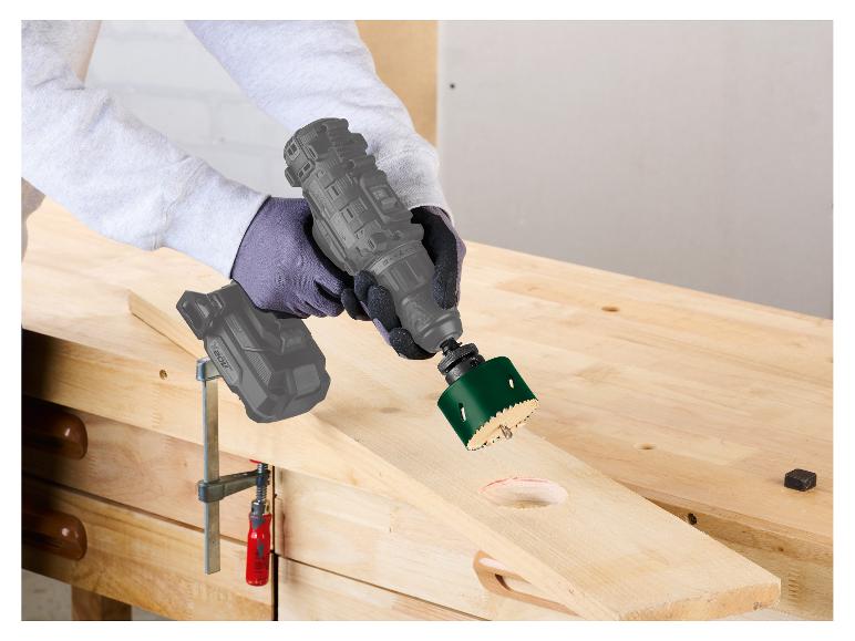 Une personne utilise une perceuse avec une scie cloche pour couper une planche de bois.