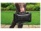 Un homme transporte un barbecue Grill Meister noir compact.