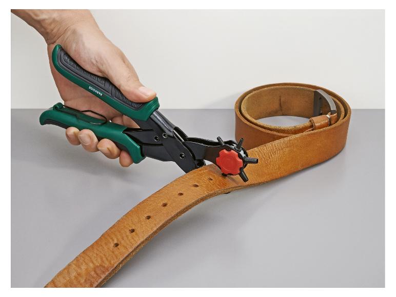 Une main utilise une pince perforatrice Parkside pour faire des trous dans une ceinture en cuir marron.