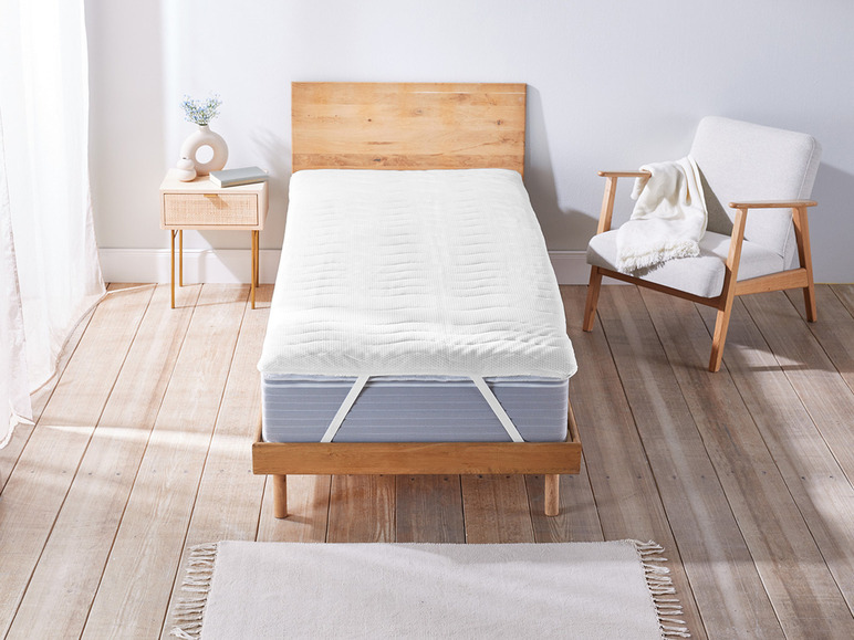 Un protège-matelas blanc sur un cadre de lit en bois.