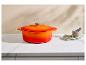 Cocotte en fonte émaillée orange sur un comptoir avec un mortier et des feuilles de laurier.