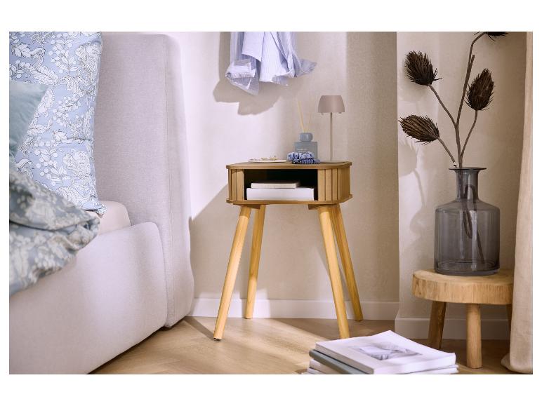 Chambre avec une table de chevet en bois, un lit gris et un vase avec des fleurs séchées.