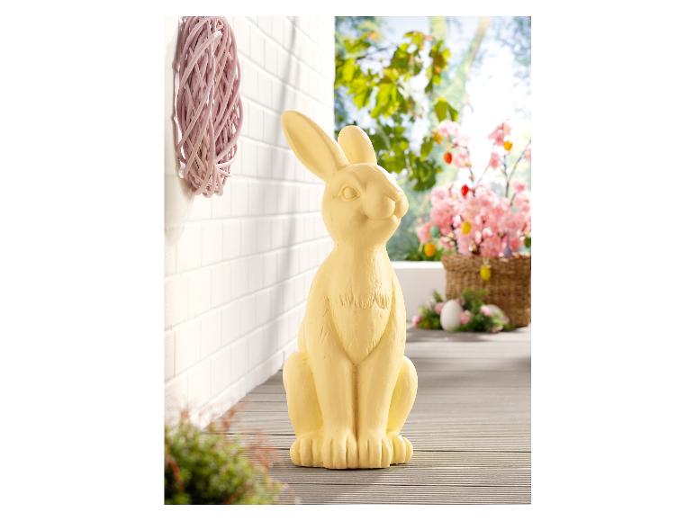 Une figurine de lapin de Pâques jaune, adaptée pour le jardin ou la terrasse.