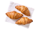 Trois croissants dorés sur une serviette blanche, vus d'en haut.