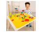 Enfant joyeux jouant avec de la pâte à modeler et des accessoires sur un tapis jaune.