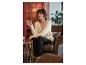 Une femme portant un cardigan blanc et un pantalon noir est assise dans un fauteuil en cuir.
