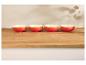 Quatre bols en céramique rouges et oranges sur une table en bois.