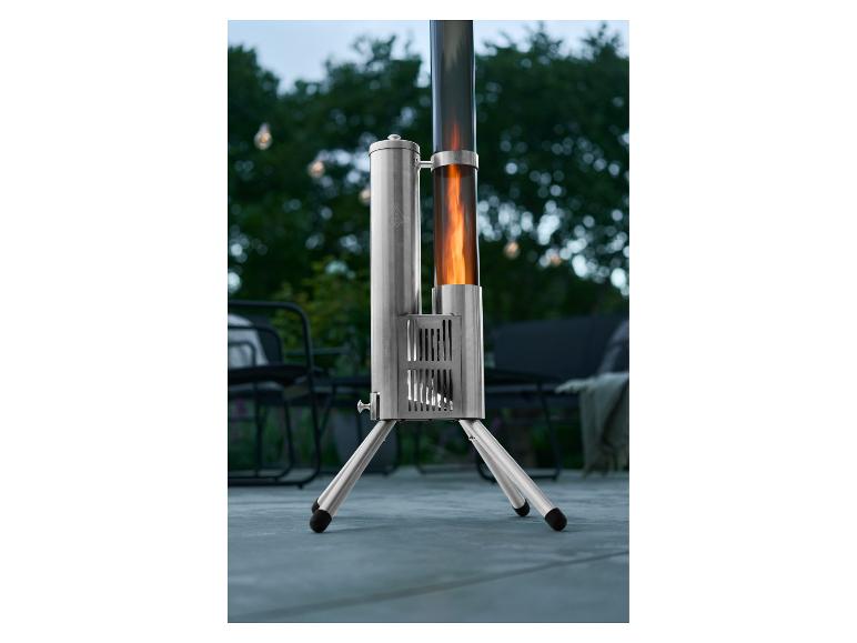 Chauffage de terrasse argenté avec flamme dans un tube en verre, placé à l'extérieur.