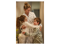 Une mère embrasse ses deux enfants dans une entrée.