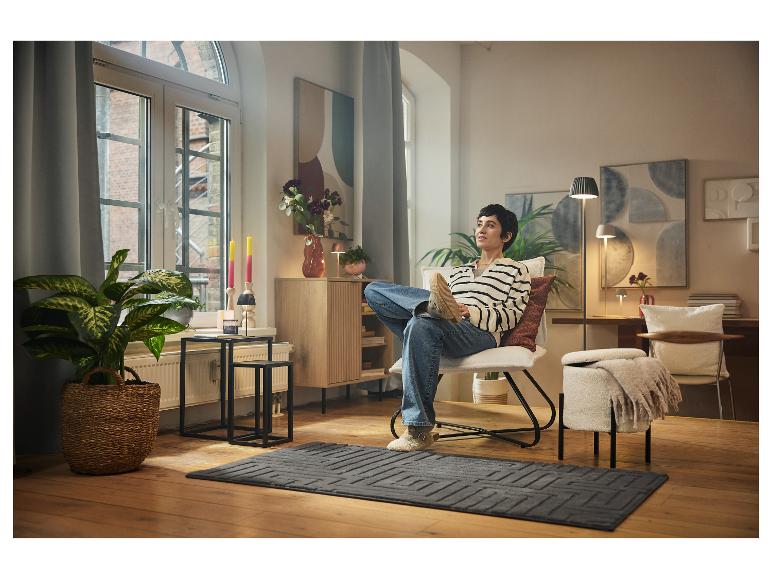 Femme se relaxant dans un fauteuil à la maison, entourée de meubles et de décorations de style scandinave.