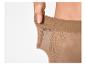 Main de femme étirant la ceinture d'un collant couleur chair, démontrant l'élasticité.