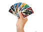 Une main tient des cartes de jeu conçues par des fans avec des personnages et des chiffres.