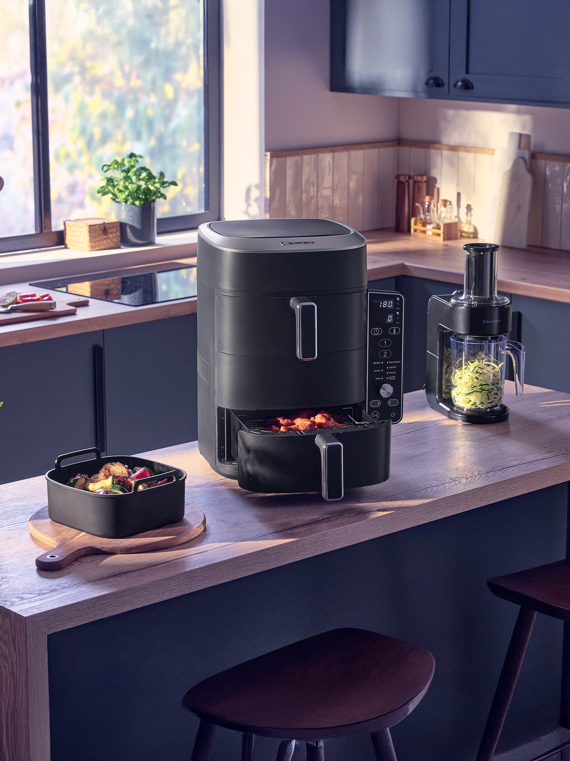 Friteuse à air et robot culinaire dans une cuisine moderne avec des plats préparés.