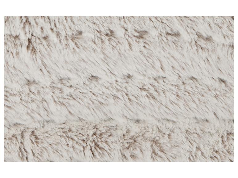 Gros plan d'une texture de fausse fourrure douce et claire avec de subtiles nuances brunes.