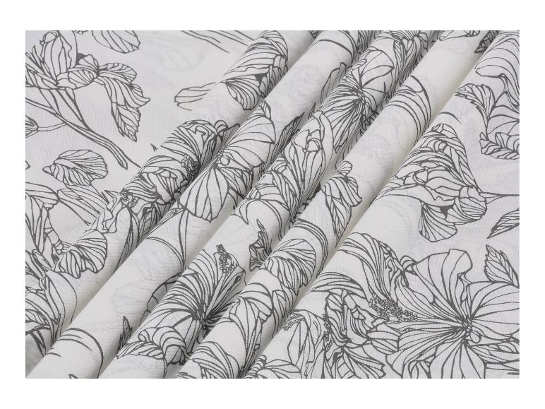 Tissu blanc avec un motif floral noir, drapé en plis.