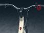 Le guidon d'un vélo électrique blanc avec un bouton plus et un bouton rouge.