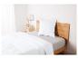 Draps blancs sur un lit en bois avec un oreiller.