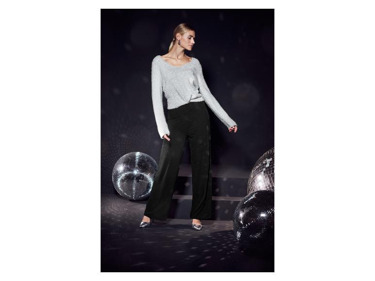 Femme en pull argenté et pantalon noir avec des boules disco.