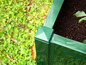 Jardinière verte avec de la terre et une plante.