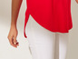 Gros plan sur un top rouge et un jean blanc.