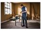 Homme en gilet et pantalon de travail Parkside utilisant une perceuse Parkside dans un atelier.