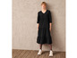 Une femme portant une robe noire et des baskets blanches.