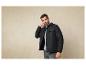 Un homme portant une veste noire et un pull gris.
