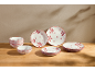Vaisselle blanche à flocons rouges: bols et assiettes sur une table en bois.