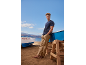 Homme en t-shirt bleu et pantalon beige sur la plage avec des bateaux, numéro 7GC305.95