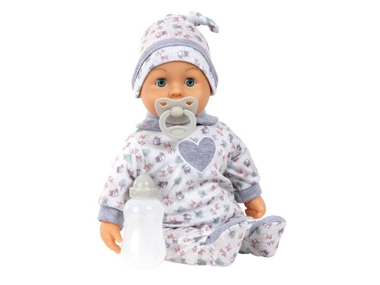 Poupée bébé en grenouillère et bonnet à motifs avec une tétine et un biberon.