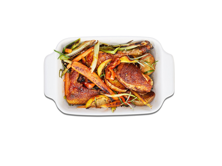 Cuisses de poulet rôties avec des pommes de terre, des carottes et des oignons nouveaux.